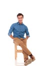Happy seated man with hands in pockets is laughing