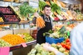 Happy seller helping customer to buy vegetables Royalty Free Stock Photo