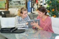 Happy seller with tablet pc helping woman with choosing flower