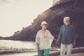 Happy senior adult couple in love waing and smiling enjoying the summer time on the beach and the retired lifestyle of their new Royalty Free Stock Photo