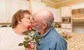 Happy Senior Adult Man Giving Red Rose to His Wife In a Kitchen Royalty Free Stock Photo