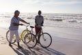 Happy senior african american couple with bicycles walking together on the beach Royalty Free Stock Photo