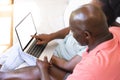 Happy senior african american couple on couch using laptop with copy space in sunny living room Royalty Free Stock Photo