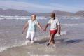 Happy senior african american couple holding hands and having fun on the beach Royalty Free Stock Photo