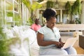 Happy senior african american couple in sunny living room, the woman on couch using laptop Royalty Free Stock Photo