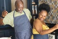 Happy senior african american couple wearing aprons and dancing in kitchen Royalty Free Stock Photo