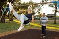 Happy senior American couple around 70 years old enjoying at swing park with husband pushing wife smiling and having fun Royalty Free Stock Photo