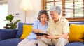 Happy senior asian couple using digital tablet computer sitting on sofa at home living room background, senior people and Royalty Free Stock Photo