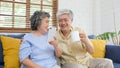 Happy senior asian couple using smart phone while sitting on sofa at home living room background, active senior people retirement Royalty Free Stock Photo