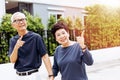 Happy senior Asian couple walking and pointing in outdoor park and house. Warm tone with sunlight.