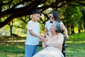 Happy senior Asian grandmother uses wheelchair with her daughter and grandchild in park, Grandson came to visit elderly