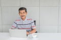 Happy Senior asian man, Smiling. front on the desk. there are laptop computer with white coffee mug Royalty Free Stock Photo