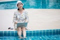 happy Senior asian woman working on  laptop computer sitting at poolside with put her legs in the water . relaxation retirement Royalty Free Stock Photo