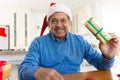 Happy senior biracial man in santa hat holding christmas present, making video call