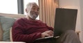 Happy senior biracial man using laptop for video call, unaltered, in slow motion