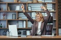 Happy senior businesswoman sitting in the office at the desk, looking at the laptop screen and enjoying good news Royalty Free Stock Photo