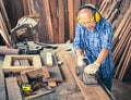 Happy senior carpenter using an electric planer