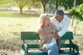 Happy senior caucasian couple hugging together at the bench in park.Elder man wrap woman with warm shirt and look at each other Royalty Free Stock Photo