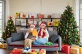 Happy Senior Caucasian couple in Santa hat sitting together on sofa couch holding hot drink at home with decorated Christmas tree Royalty Free Stock Photo