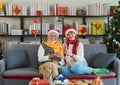 Happy Senior Caucasian couple wearing Santa hat sitting on sofa couch holding and cheers champagne flute together at home in cozy Royalty Free Stock Photo