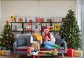 Happy Senior Caucasian couple wearing Santa hat sitting together on sofa couch holding Christmas gift at home with decorated Royalty Free Stock Photo