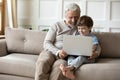 Happy mature grandfather and little grandson use laptop