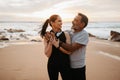 Happy senior caucasian man in sportswear hugs wife in headphones, enjoy love, relationships, training and sports Royalty Free Stock Photo