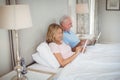 Happy senior couple on bed using laptop and digital tablet Royalty Free Stock Photo