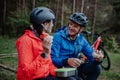 Happy senior couple bikers with eating snack outdoors in forest in autumn day. Royalty Free Stock Photo