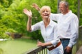 Happy senior couple on bridge waving hands Royalty Free Stock Photo