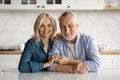 Happy senior couple in casual outfits posing together at cozy kitchen interior Royalty Free Stock Photo