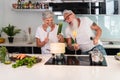 Happy senior couple dancing while cooking together at home - Mature people having fun preparing the lunch - Joyful elderly Royalty Free Stock Photo