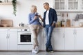 Happy senior couple drinking red wine at kitchen, full length Royalty Free Stock Photo