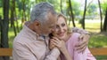 Happy senior couple embraces in park, man hugging woman, love until old age Royalty Free Stock Photo