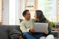 Happy senior couple embracing and using laptop together on couch. Retired people lifestyle concept Royalty Free Stock Photo