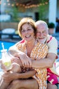 Happy senior couple enjoying drinks when relaxing and sitting by swimming pool in summer. Royalty Free Stock Photo