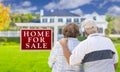 Happy Senior Couple Front of For Sale Sign and House Royalty Free Stock Photo