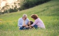 Senior couple with granddaughter outside in spring nature, relaxing on the grass. Royalty Free Stock Photo