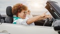 Happy senior couple having fun in convertible car during summer vacation - Focus on african woman face Royalty Free Stock Photo