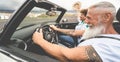 Happy senior couple having fun in convertible car during summer vacation - Focus on hipster man face Royalty Free Stock Photo