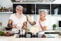 Happy senior couple having fun cooking together at home - Elderly people preparing health lunch in modern kitchen Royalty Free Stock Photo