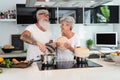 Happy senior couple having fun cooking together at home - Elderly people preparing health lunch in modern kitchen Royalty Free Stock Photo