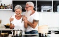 Happy senior couple having fun cooking together at home - Elderly people preparing health lunch in modern kitchen Royalty Free Stock Photo