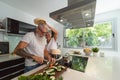 Happy senior couple having fun cooking together at home - Elderly people preparing health lunch in modern kitchen Royalty Free Stock Photo