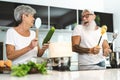 Happy senior couple having fun cooking together at home - Elderly people preparing lunch in modern kitchen Royalty Free Stock Photo