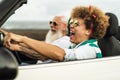 Happy senior couple having fun driving on new convertible car - Mature people enjoying time together during road trip Royalty Free Stock Photo