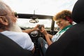 Happy senior couple having fun taking photo with old vintage camera while driving on new convertible car during road trip Royalty Free Stock Photo