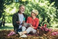 Senior couple having a picnic in park using digital tablet and credit card for online shopping