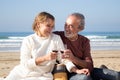 Happy senior couple having picnic at seashore on sunny afternoon Royalty Free Stock Photo