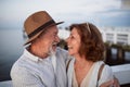 Happy senior couple hugging outdoors on pier by sea, looking at each other. Royalty Free Stock Photo